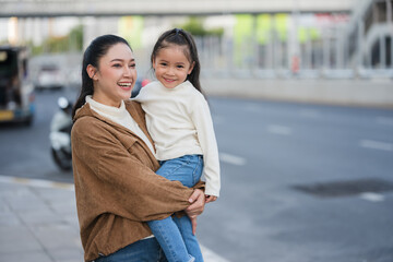 Fototapeta premium mother holding daughter on city street