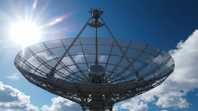 Large Satellite Dish Antenna Under Bright Blue Sky with Moving Clouds and Sun Flare