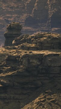 Sunlight kisses the rugged cliffs as shadows dance across the desert landscape. The expansive scenery showcases the intricate shapes of ancient rock formations, creating a serene atmosphere.