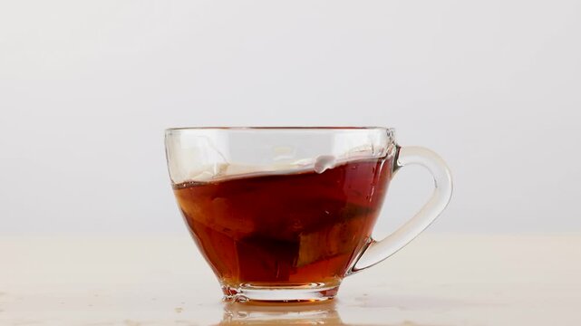 Slow Motion Splash of Hot Tea in Clear Glass Cup