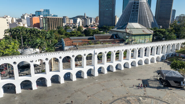 Arcos da Lapa featuring its iconic white arches stretching across the urban landscape with surrounding buildings and clear sky in Rio de Janeiro, Rio de Janeiro, Brazil. Aerial view.