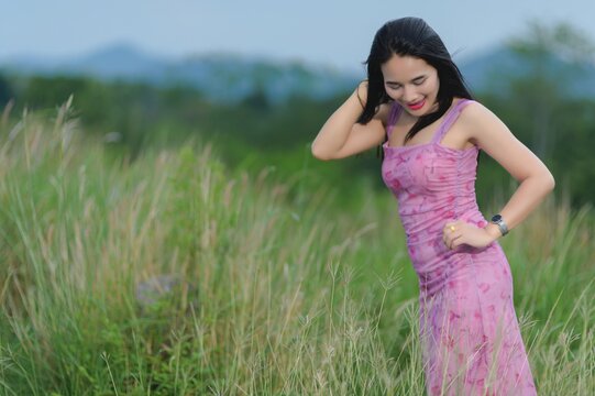 Woman in Pink Outfit Posing in Grass at Sai Thong Reservoir, Thailand