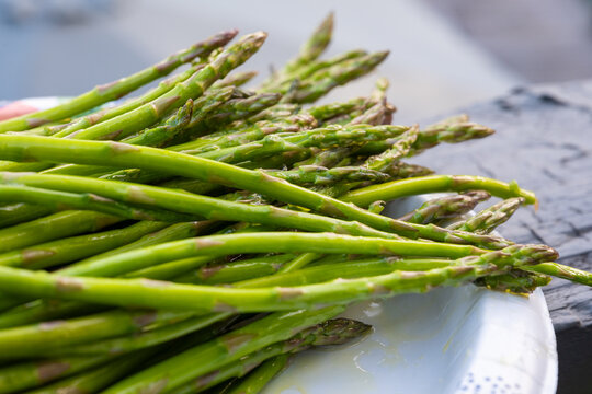 Close up photo of fresh green asparagus spears on a plate with shallow depth of field.