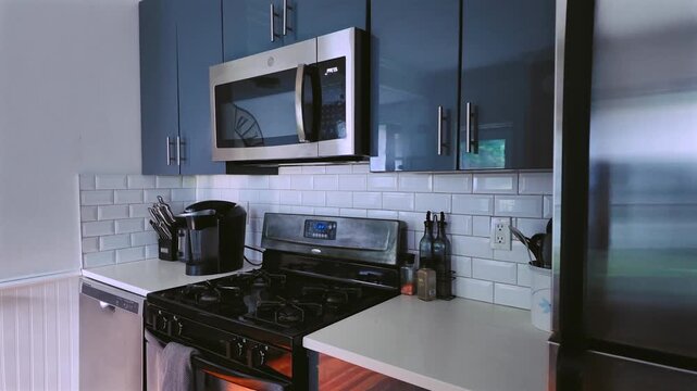  Interior of a modern kitchen in a modest home, Interior of a blue cabin kitchen featuring metallic elements and a microwave oven.