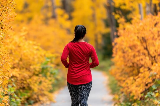 Woman runner jogging on a scenic autumn trail through the vibrant yellow forest