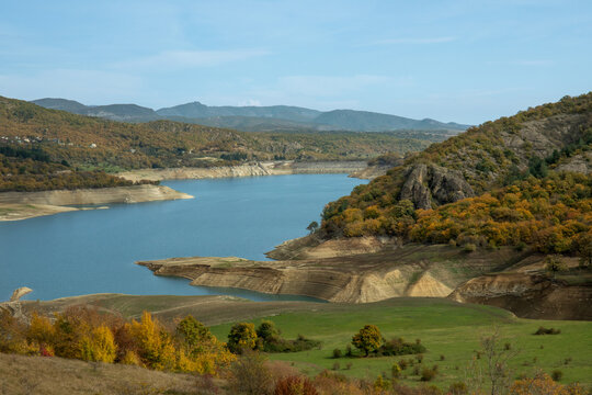 Calm lake reflects colorful autumn foliage in mountainous terrain