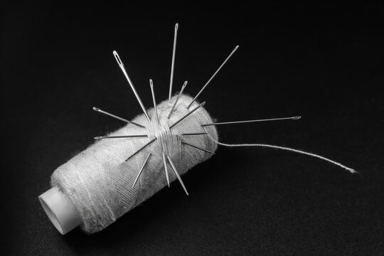 White thread and needles isolated black background 