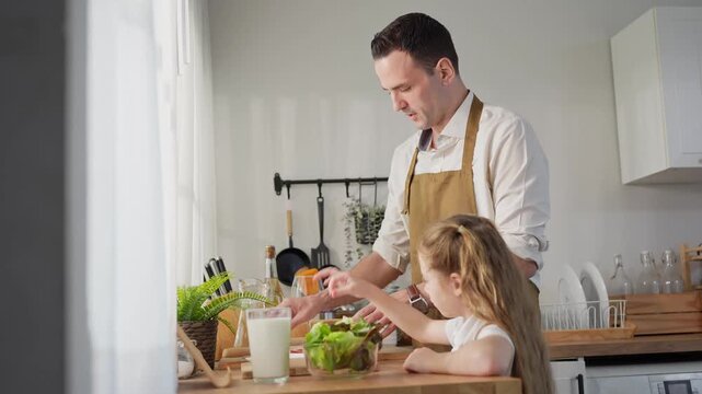 Father and daughter preparing healthy food together in modern kitchen, Happy young girl helping father cook meal at home, Family time cooking concept with dad and daughter in domestic kitchen