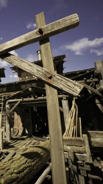 In a sunlit scene, an old wooden structure features rustic beams and weathered planks. Surrounding remnants hint at former life, inviting curiosity about its history and story.
