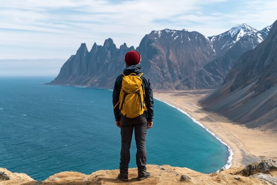 Hiker and traveler on a mountain cliff edge in senja norway overlooking the fjord