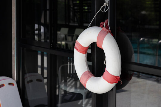 Lifebuoy hangs on dark-framed glass door near pool area