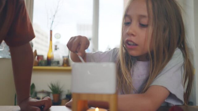 Siblings taking turns dipping into a chocolate fondue pot with long forks