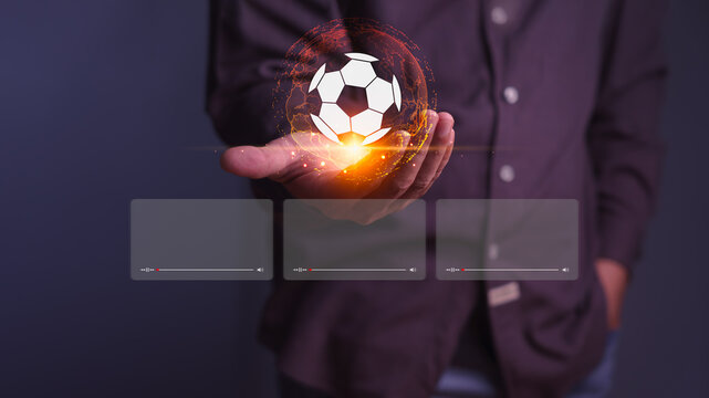 Adult man holds a virtual digital soccer and football sport hologram. This modern technology provides live video streaming and advanced broadcasting for global online viewing.