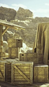 Sunlight casts a warm glow on rustic wooden crates arranged at a mountain site. A cloth partially covers a crate, adding mystery to this serene outdoor scene, evoking a sense of exploration.