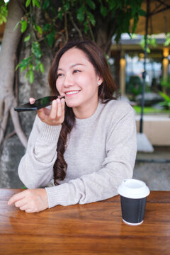Vertical image of a woman holding smart phone and using voice messaging, talking with ai assistant for Artificial intelligence concept