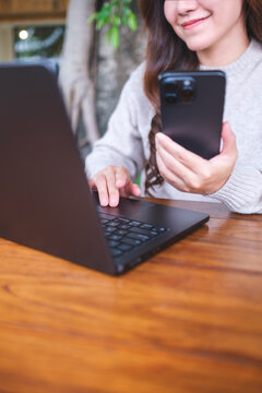 Vertical closeup image of a businesswoman using smart phone and laptop computer