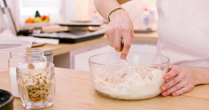 Cooking treat. Baker occupation. Woman hand kneading soft dough spoon in with preparing tasty home recipe pastry on table with peanut jar.