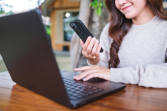Closeup image of a businesswoman using smart phone and laptop computer