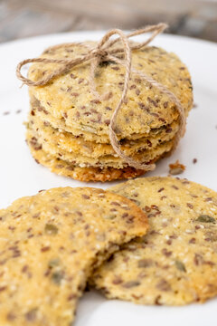Crunchy biscuits. Diet snack. Round crispbread stack tied craft rope placed on white plate. Tasty bitten cookies with flax seeds background.