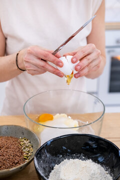 Culinary work. Treat preparation. Woman chef hand cracking eggs in glass bowl with butter sugar cooking sweet pastry at home kitchen.
