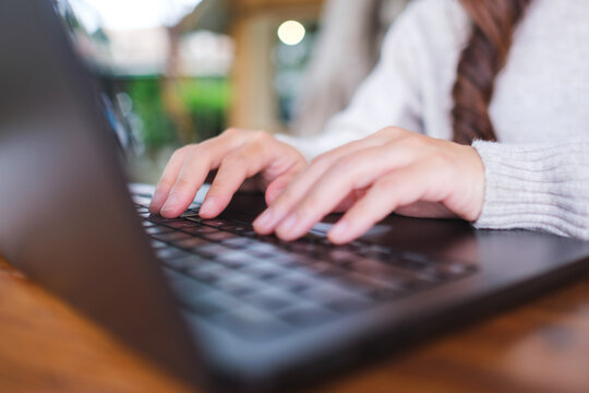 Closeup image of a woman working and typing on laptop computer keyboard