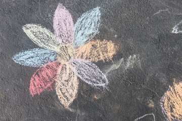 child's drawing of daisy with rainbow petals with concrete chalks on driveway © faithie