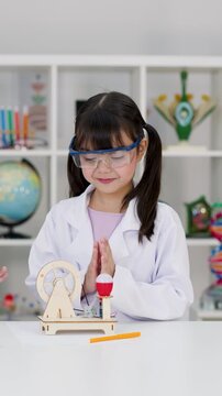 Young Girl in Lab Coat Testing Science Experiment Kit in Classroom