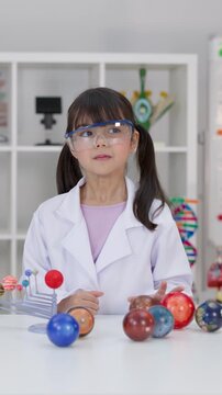 Elementary School Girl in Lab Coat Studying Solar System Model