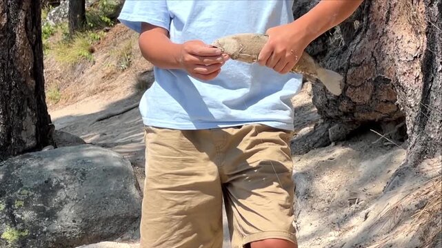 Adult man holding fishing tackle near a mountain lake in Idaho, USA, angling preparation, outdoor hobby, recreational adventure, summer lifestyle.