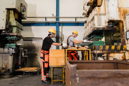 Operators adjusting die tooling between two industrial stamping presses ensuring precision and quality in a modern industrial manufacturing environment with heavy machinery