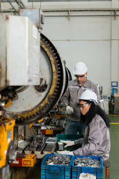 Two factory workers examining tooling near power press flywheels and dies