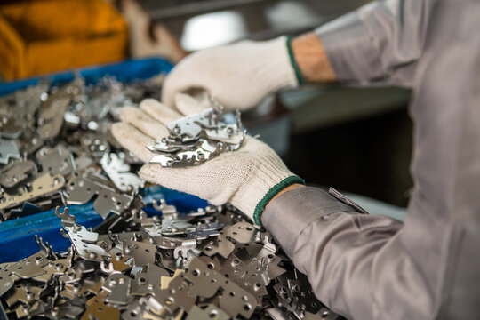 Gloved Hands Sorting Freshly Stamped Sheet Metal Brackets In Factory Bin