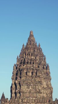 Frontal vertical view highlights the tiered stone crown and intricate sacred architecture of a Prambanan Temple tower.