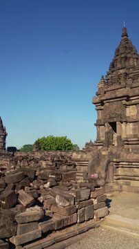 Ancient Prambanan shrine rises beside extensive weathered ruins within the historic Hindu temple complex of Central Java.