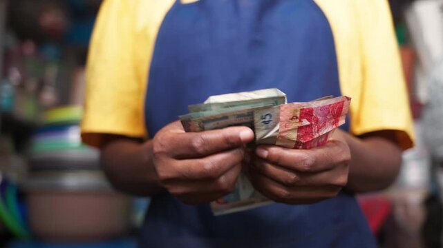 African woman entrepreneur holding her earnings in her shop, business growth and financial success
