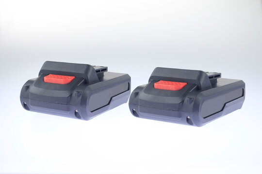 Two sleek black batteries with red accents sit side by side. Minimalist studio lighting highlights their rugged design. Clean background emphasizes utility modern functionality, tools and portable.