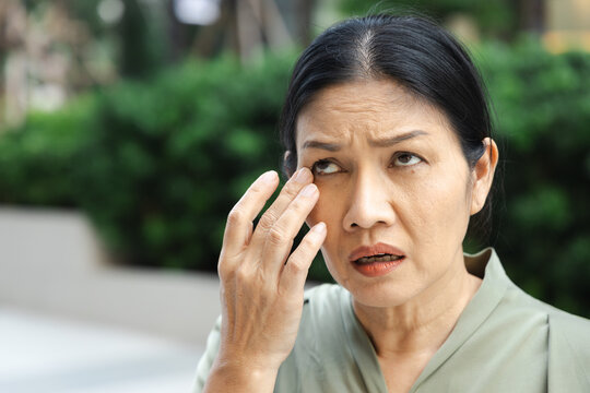 Middle aged Asian woman touching eyelid bump old aged health condition