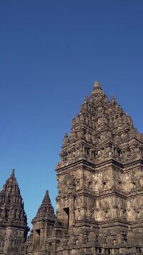 Majestic Prambanan Temple tower rises among smaller spires beneath a vivid blue sky in Central Java, Indonesia.