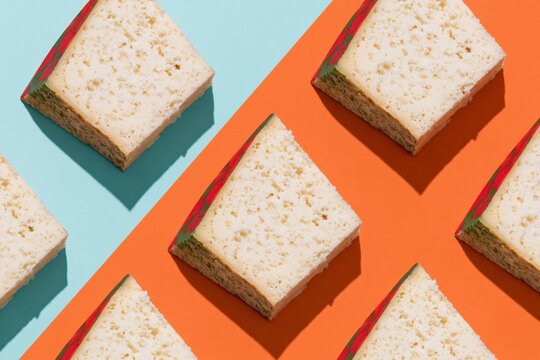 Creamy cheese slices in a repeating geometric pattern on a bold blue and orange background, viewed from above for culinary packaging and food brand design