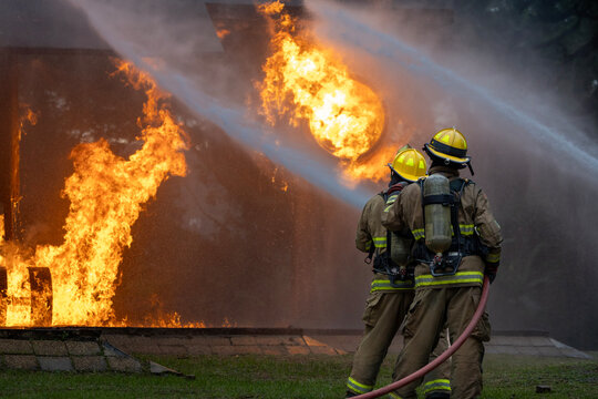 Team of firefighter in fireproof clothe using the fog watering hose to put out the burning crashing plane with high flame for fire extinguish risk rescue mission and accident