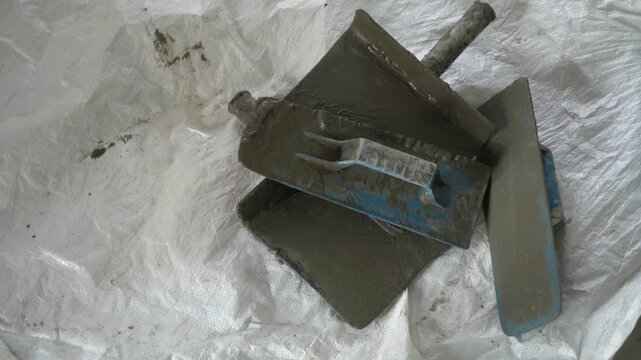 Plasterer trowels and masonry hand tools placed on a bag of cement.