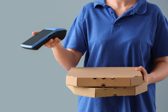 Delivery person in blue uniform holding pizza boxes and a payment terminal for contactless transactions, Modern food delivery services and convenient contactless payment options