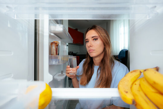 Tired Woman Trying To Hydrate With Cold Water In The Morning. Exhausted lady holds a refreshing glass trying to wake up early today