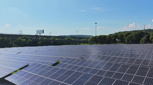 Drone moving over solar panels with highway traffic beyond