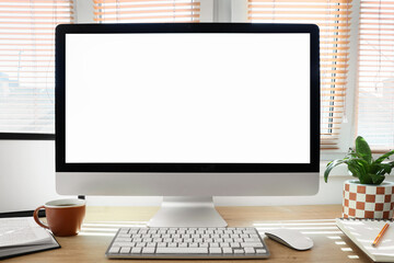 Fototapeta premium Workplace with blank computer monitor near window in office