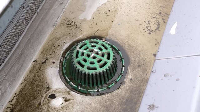 High angle view of a rainwater drainage outlet on a flat concrete roof.