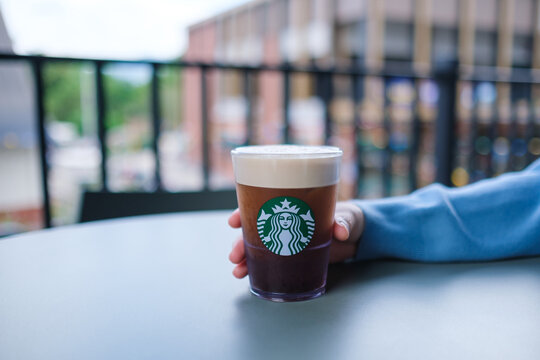Jul 11th 2026 : A hand holding a glass of iced Aerocano coffee at Starbucks coffee shop, Chiang Mai Thailand