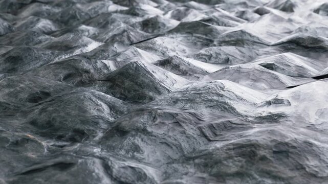 Seamless loop 3D animation of abstract dark grey stone landscape with organic undulating waves, glossy surface texture, and shallow depth of field. Perfect background for modern tech presentations, mo
