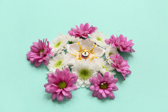 Diya lamp with flowers on turquoise background. Divaly celebration