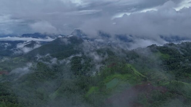 After summer rain with fog and clouds hanging over green forest hills in the national park of thailand. Aerial view